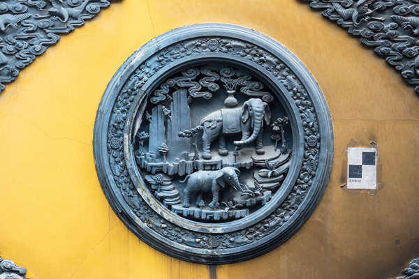 Elephants sculpted into a medallion on the yellow wall of a temple in India.